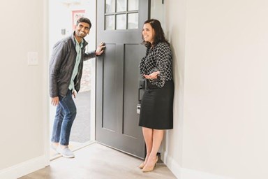 Man walking into a property and a woman greeting him.